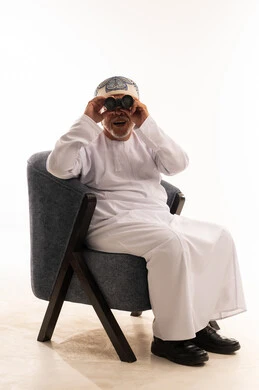 Elderly Omani Man in Traditional Dress Using Binoculars
