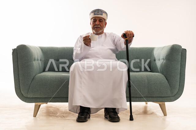 رجل عماني مسن بالزي التقليدي مع عصا مشي