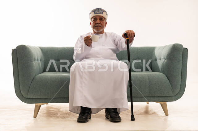 Elderly Omani Man in Traditional Dress on Green Sofa