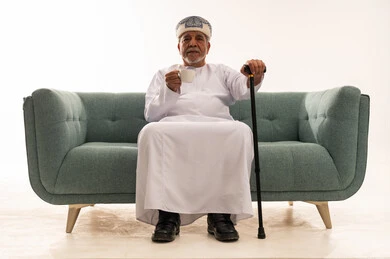 Elderly Omani Man in Traditional Dress on Green Sofa