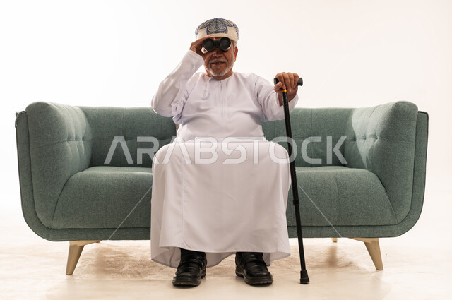 Elderly Omani Man with Binoculars on Studio Sofa