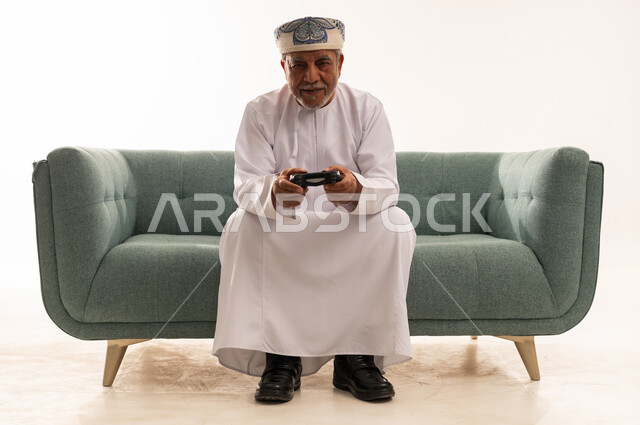 Elderly Omani Man Playing Video Games in Traditional Dress
