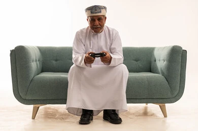 Elderly Omani Man Playing Video Games in Traditional Dress