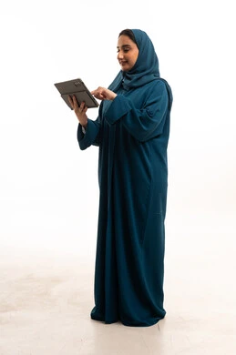 امرأة سعودية بالعباءة تستخدم جهازاً لوحياً بخلفية بيضاء