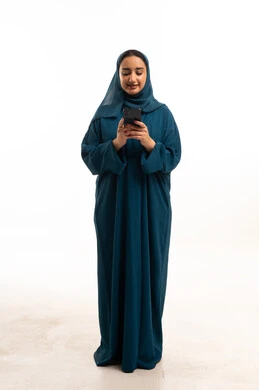 امرأة سعودية بعباءة زرقاء تستخدم الجوال