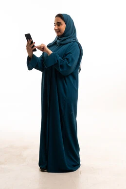 امرأة سعودية بعباءة ملونة تستخدم الهاتف المحمول