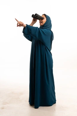 امرأة إماراتية بالعباية تنظر بالمنظار خلفية بيضاء