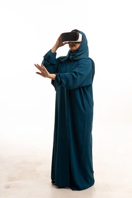 امرأة عربية بعباءة زرقاء تستخدم نظارات الواقع الافتراضي