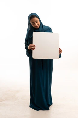 امرأة سعودية بعباءة خضراء تحمل لوحة بيضاء فارغة