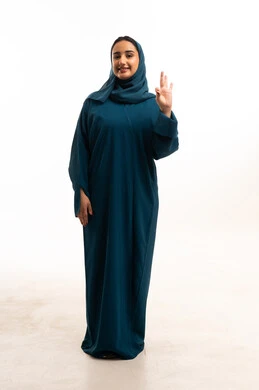 امرأة إماراتية بعباءة زرقاء تقوم بإشارة الموافقة