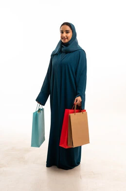 امرأة إماراتية بعباءة تيل تحمل حقائب تسوق