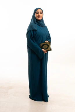 امرأة عربية بعباءة ملونة تمسك القرآن الكريم