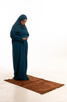 امرأة سعودية تصلي بالعباءة على خلفية بيضاء
