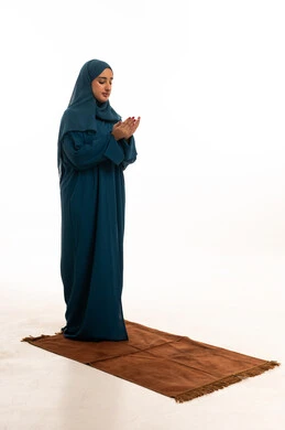 امرأة إماراتية تصلي بعباءة زرقاء على خلفية بيضاء