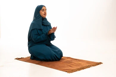 امرأة عربية مسلمة محجبة تدعو على سجادة الصلاة