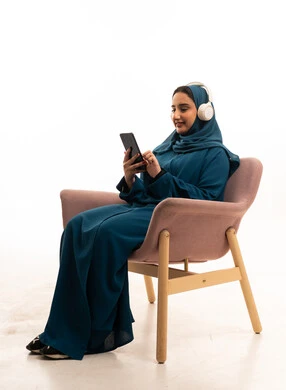 Saudi Woman in Abaya Using Smartphone and Headphones