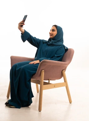 امرأة إماراتية بالعباءة تلتقط سيلفي في الاستوديو