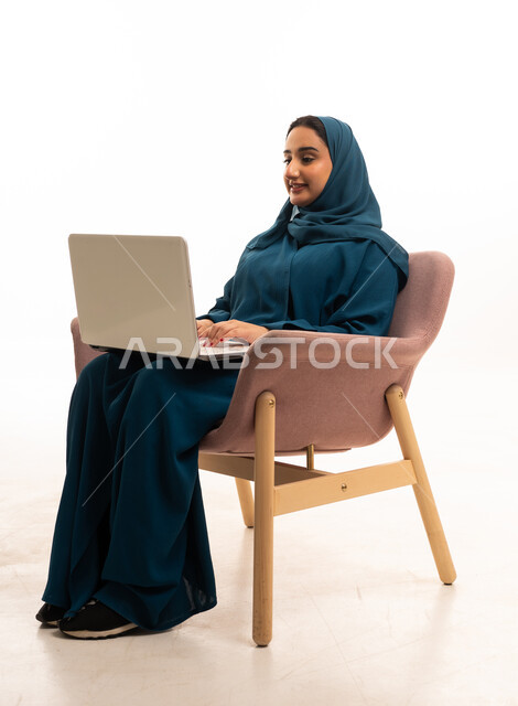 امرأة سعودية تستخدم الكمبيوتر المحمول بخلفية بيضاء