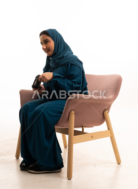 امرأة سعودية تحمل جهاز تحكم ألعاب في الاستوديو