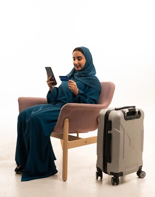امرأة سعودية مع بطاقة ائتمان وحقيبة سفر