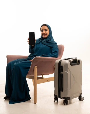 امرأة سعودية مع هاتف ذكي وحقيبة سفر