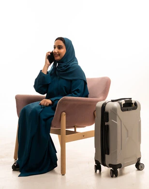 امرأة سعودية مع حقيبة سفر تتحدث بالهاتف المحمول