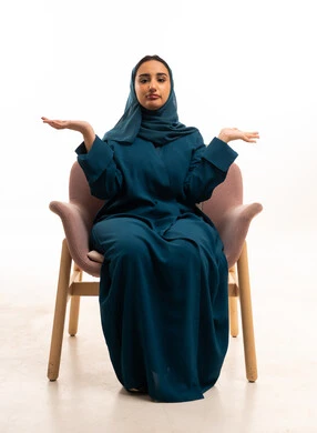 امرأة إماراتية بالعباءة والحجاب تجلس في استوديو