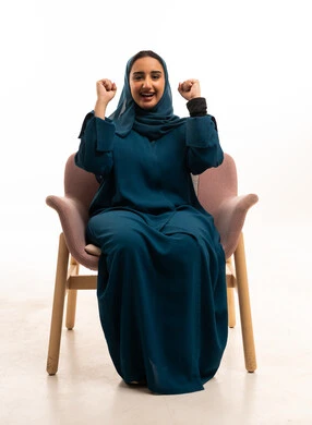 امرأة إماراتية بعباءة كحلية تحتفل على خلفية بيضاء