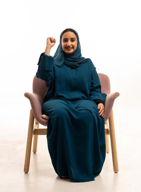 امرأة سعودية بالعباءة ترفع قبضتها علامة للنصر