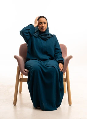 Emirati Woman in Abaya Sitting with Headache Pain