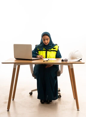 مهندسة سعودية تعمل على مكتب مع كمبيوتر محمول