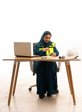 مهندسة سعودية تعمل على المكتب مع أدوات السلامة