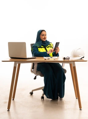 Emirati Female Engineer Using Smartphone at Office Desk Emirati Female Engineer Using Smartphone at Office Desk