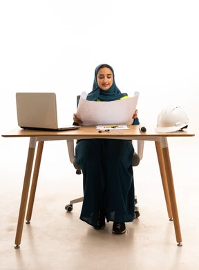 مهندسة سعودية تعمل على مخططات هندسية في المكتب