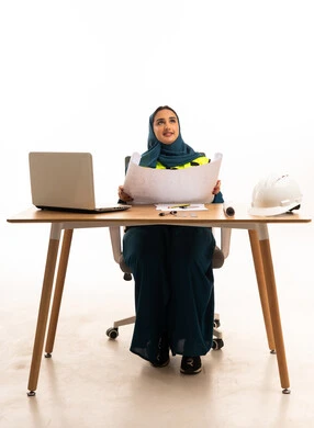 مهندسة سعودية مع مخططات هندسية على مكتب العمل