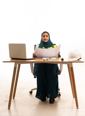 مهندسة سعودية مع مخططات هندسية على مكتب العمل
