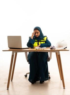 Saudi Female Engineer Stressed at Desk with Blueprints