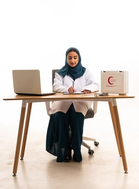 طبيبة سعودية تكتب خلف مكتب طبي