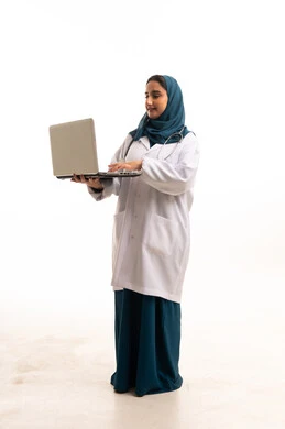 طبيبة سعودية محجبة تستخدم الحاسوب المحمول بالمعطف الأبيض