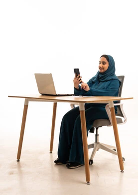 امرأة سعودية بالعباءة تستخدم الهاتف على مكتب العمل