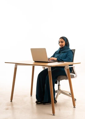 امرأة سعودية تعمل على لابتوب مع سماعات مكتبية