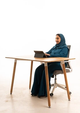 امرأة سعودية بالعباءة تستخدم جهاز لوحي في المكتب