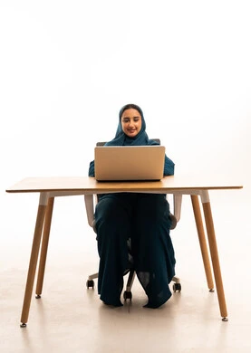امرأة إماراتية تعمل على كمبيوتر محمول في مكتبها