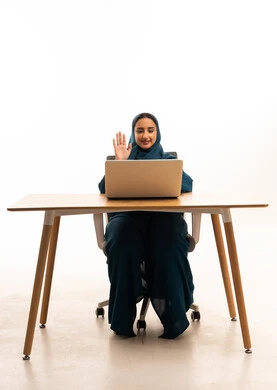 Saudi Woman Using Laptop for Video Call at Desk