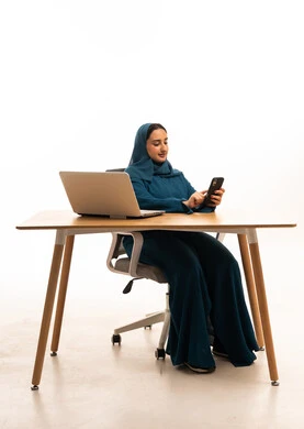 Saudi Businesswoman Using Smartphone at Office Desk