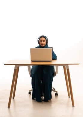 Emirati Woman on Laptop with Headphones White Background