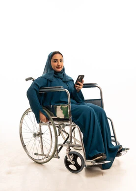 امرأة سعودية على كرسي متحرك مع هاتف ذكي بخلفية بيضاء