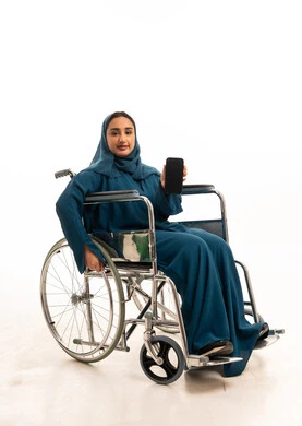 امرأة سعودية على كرسي متحرك تحمل هاتفا ذكيا