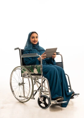 امرأة إماراتية على كرسي متحرك تستخدم جهازاً لوحياً