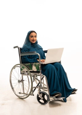 امرأة سعودية على كرسي متحرك مع لابتوب بعباية زرقاء